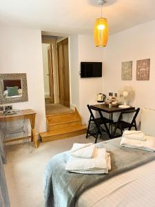 a room with a bed and a table and a television at The Gower Hotel in Swansea