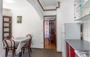 a kitchen with a table and chairs and a refrigerator at 2 Bedroom Lovely Apartment In Njivice in Njivice