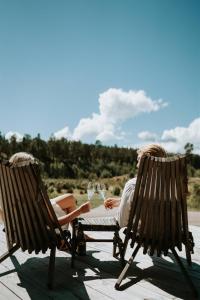 two people sitting in chairs on the beach with wine glasses at Tackork Gård & Marina in Nauvo