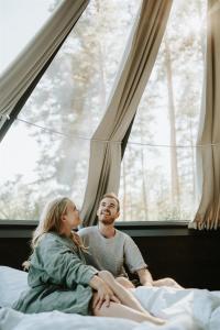 Ein Mann und eine Frau sitzen auf einem Bett und schauen aus dem Fenster in der Unterkunft Tackork Gård & Marina in Nauvo