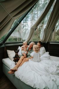 a family sitting on a bed in a tent at Tackork Gård & Marina in Nauvo