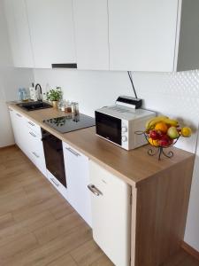 a kitchen with a microwave and a bowl of fruit on a counter at Complex Apartamenty - Golden in Koszalin