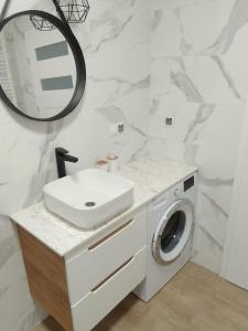 a white bathroom with a sink and a washing machine at Complex Apartamenty - Golden in Koszalin
