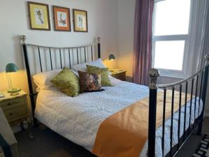um quarto com uma cama com almofadas e uma janela em "The Quirky" Seafront Apartment em Eastbourne