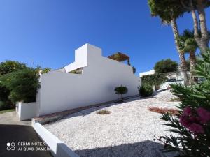 una casa blanca con una pared blanca y palmeras en Pareado en Loma Sancti Petri a 900 m de la playa de La Barrosa en Chiclana de la Frontera