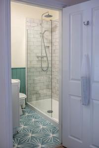 a bathroom with a shower and a toilet with a glass door at Three Tuns in Helston