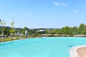 明喬河畔瓦萊焦的住宿－Agricampeggio Corte Tonolli，一个带椅子和遮阳伞的大型蓝色游泳池