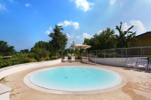 a large swimming pool with chairs and an umbrella at Agricampeggio Corte Tonolli in Valeggio sul Mincio