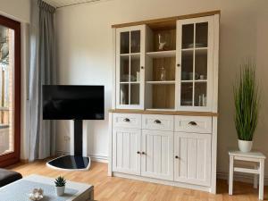 Cabaña blanca con TV en la sala de estar en Kleine Robbe Ferienhaus, en Dangast