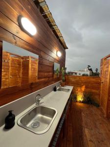 Atlit Rooftop Glamping في Atlit: مطبخ مع مغسلتين وجدار خشبي