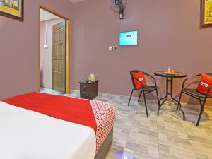 1 dormitorio con 1 cama, mesa y sillas en OYO Home 90348 Inspire Rooms en Pantai Cenang