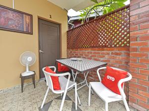 d'une terrasse avec une table, des chaises et un mur en briques. dans l'établissement OYO Home 90348 Inspire Rooms, à Pantai Cenang