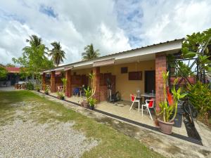Cette maison dispose d'une terrasse avec une table et des chaises. dans l'établissement OYO Home 90348 Inspire Rooms, à Pantai Cenang