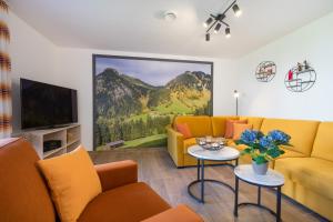 a living room with a yellow couch and a tv at Ferienwohnungen Alpentraum - Oberstdorfer Berglodge in Oberstdorf