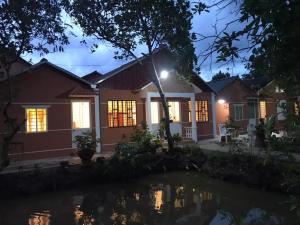a house with a pond in front of it at Nam Thanh Homestay in Vĩnh Long