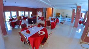 a dining room with tables and chairs with red table cloth at Hotel Al Akha in Sidi Harazem