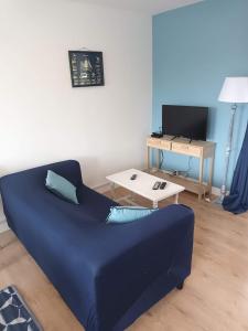 niebieska kanapa w salonie ze stołem w obiekcie La charmante Cayolaise w mieście Cayeux-sur-Mer