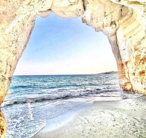 a view of the ocean through a rock cave at Governors Beach Costas Apts in Governor's Beach
