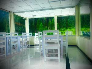 a dining room with white chairs and a large window at Valhalla Resort Kumrat in Tāl