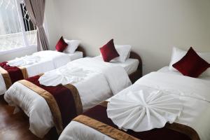 Habitación con 3 camas y almohadas blancas y rojas. en Om Tara Guest House Pvt Ltd, en Katmandú