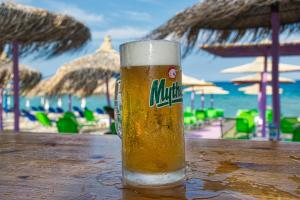 a glass of beer sitting on a table near the beach at House Blerina in Sarti