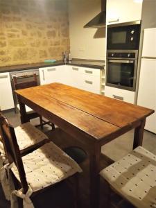 cocina con mesa de madera, 2 sillas y horno en El Desván del Campanero apartamento con jardín, en Murillo de Gállego
