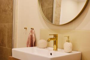 a bathroom sink with a gold faucet and a mirror at Ferienhaus in idyllischer Lage - Ankommen & durchatmen in Humptrup +17 photos