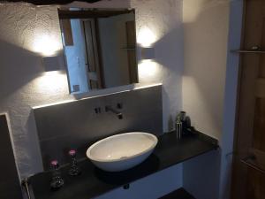 a bathroom with a sink and a mirror on a counter at Charming 3½ room cottage in Valposchiavo in Poschiavo