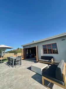 a patio with tables and chairs and a building at Living The Breede - Weaver Cottage in Malgas
