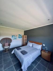 a bedroom with a large bed and a chair at Living The Breede - Weaver Cottage in Malgas