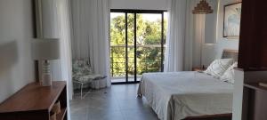 1 dormitorio con cama, ventana y silla en Superbe appartement avec vue mer et montagnes. en Tamarin