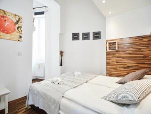 - une chambre blanche avec un grand lit et une tête de lit en bois dans l'établissement Vicus Apartment by Irundo, à Zagreb