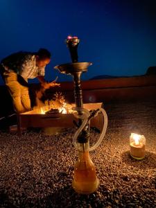 um homem parado em frente a uma mesa com uma fogueira em Desert Dream Camp em Wadi Rum