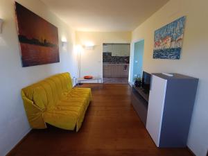 a living room with a yellow couch and a television at Moratto's Apartments in Umag