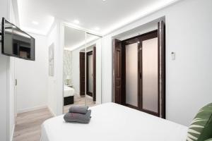 Noviciado Apartment في مدريد: غرفة نوم بيضاء مع سرير وتلفزيون