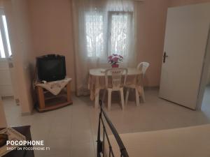 ein Wohnzimmer mit einem Tisch und einem TV in der Unterkunft Κεντρικό, άνετο και ζεστό διαμέρισμα in Kamena Vourla