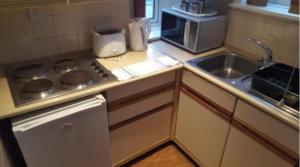 a kitchen with a sink and a stove and a microwave at Devoncourt Short Term Rentals in Exmouth