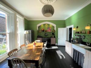 a kitchen with a wooden table and green walls at City Centre Luxury Holiday House with Outdoor Bath and Parking in York