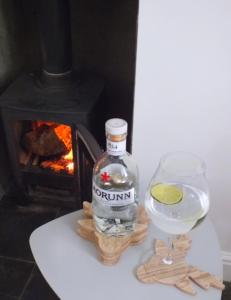 a bottle and a glass of wine next to a fireplace at Boggle Dyke Cottage in Thornhill