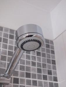 a shower head in a bathroom with gray tiles at Boggle Dyke Cottage in Thornhill