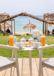 a white table with food and orange juice on the beach at Royal Azur Thalassa in Hammamet