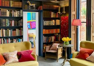 a library with two chairs and a table and books at City Centre Luxury Holiday House with Outdoor Bath and Parking in York