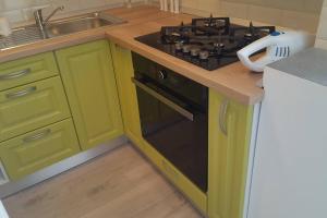 a kitchen with green cabinets and a stove top oven at Apartament cu 1 camera spatios ,luminos . in Cugir