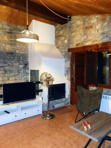 sala de estar con TV, mesa y ventilador en Masia La Clariana, en Castelltallat