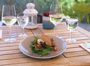 ein Teller mit Essen auf einem Holztisch mit Weingläsern in der Unterkunft Ferienbungalow Haus am Teich in Boltenhagen