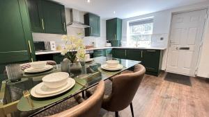 a kitchen with green cabinets and a glass table with chairs at Canalside in Headingley
