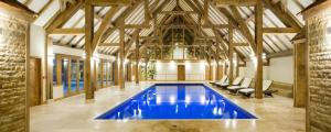 a large swimming pool in a building with wooden ceilings at Silver Birches in Wisbech