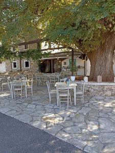 a group of tables and chairs under a tree at Lovely Studio in Strinilas with its own pool in StrinÃ½las