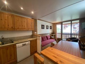 a kitchen with wooden cabinets and a pink couch at Silveralp in Val Thorens