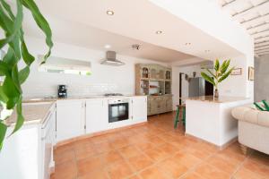 a kitchen with white cabinets and a living room at Finca Botanico Secret Garden in Guatiza